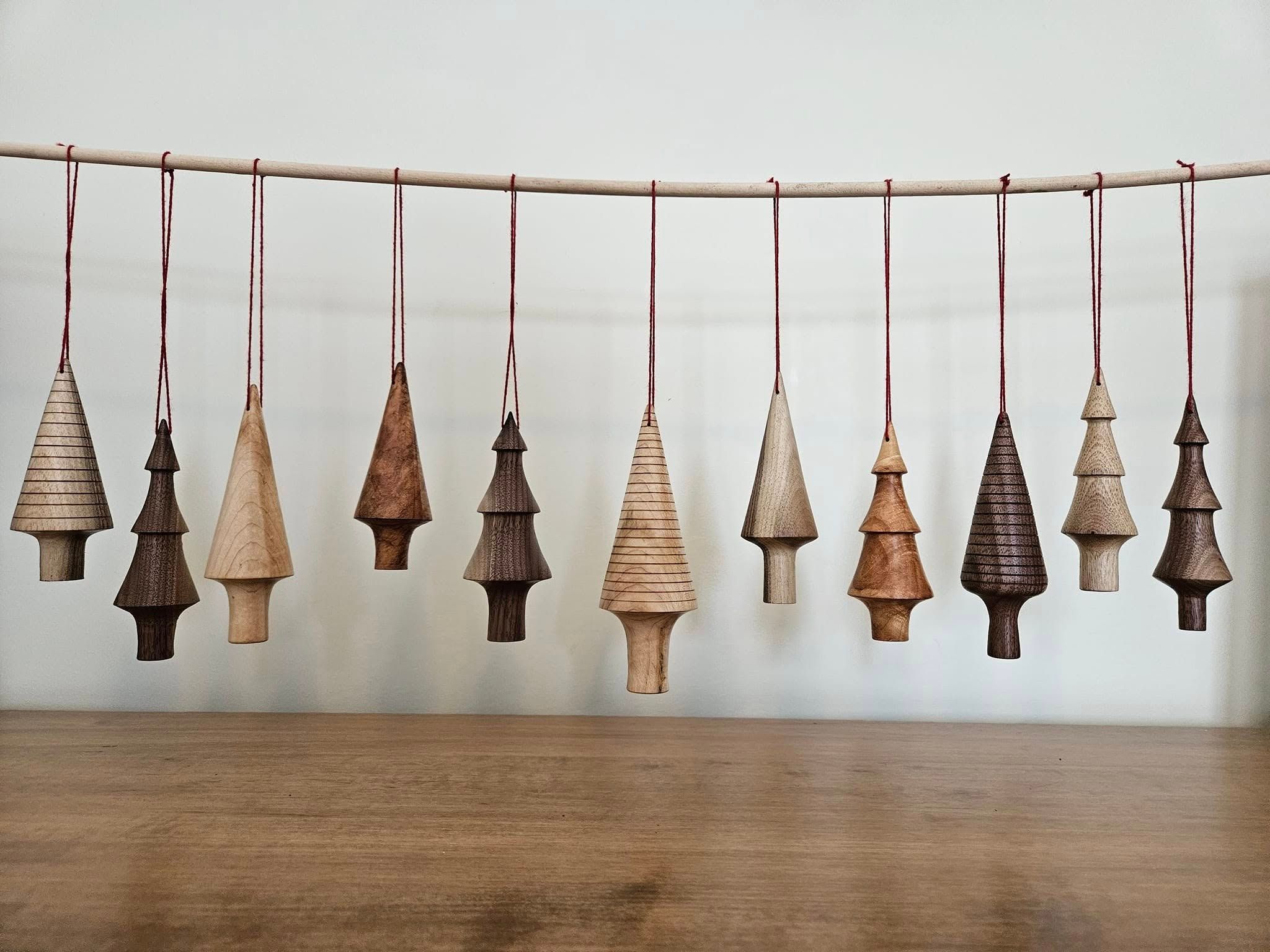 Eleven hand-turned tree ornaments hanging on red string